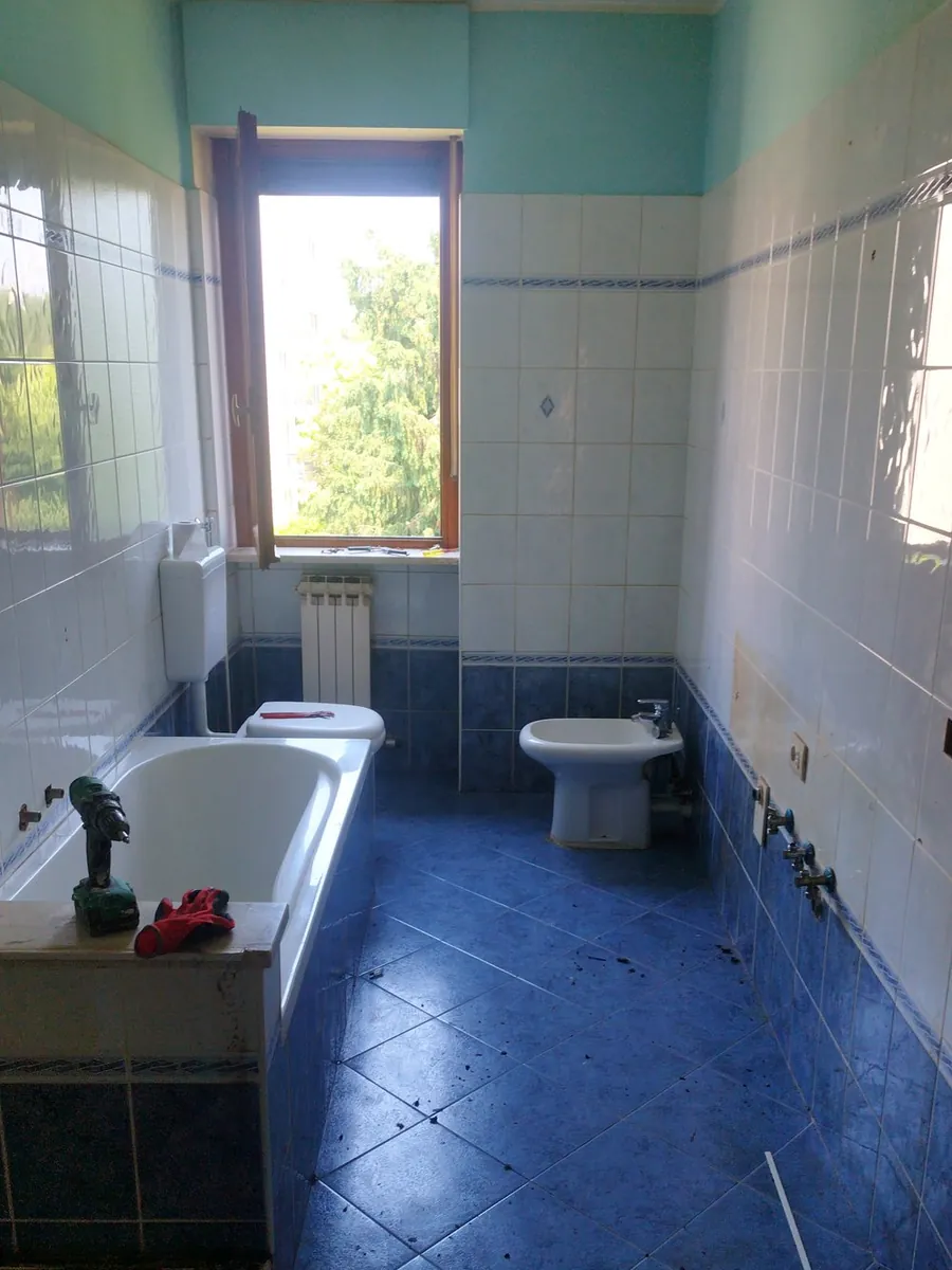 Foto originale di un bagno con vecchie piastrelle, vasca e sanitari