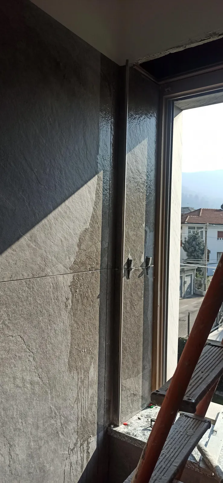 Posa di grandi lastre a parete con sistema di livellamento, accanto alla finestra — Villa in Corso Casale, Torino
